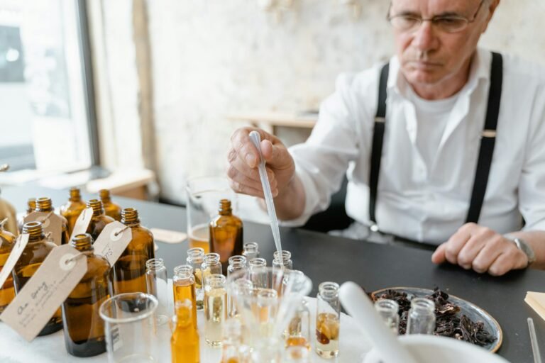 Senior male preparing natural fragrance mixtures indoors using lab tools.